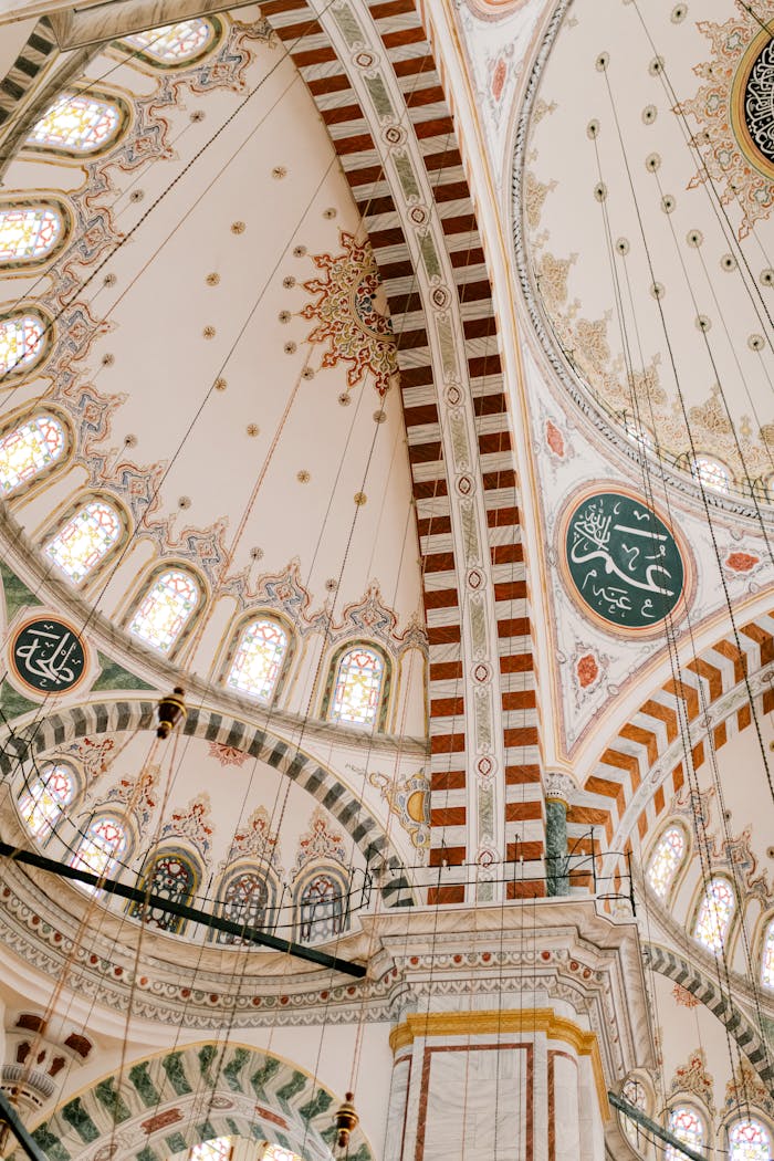 From below of high domed ceiling with colorful ornamental elements and arched windows located in Blue mosque in Istanbul Turkey